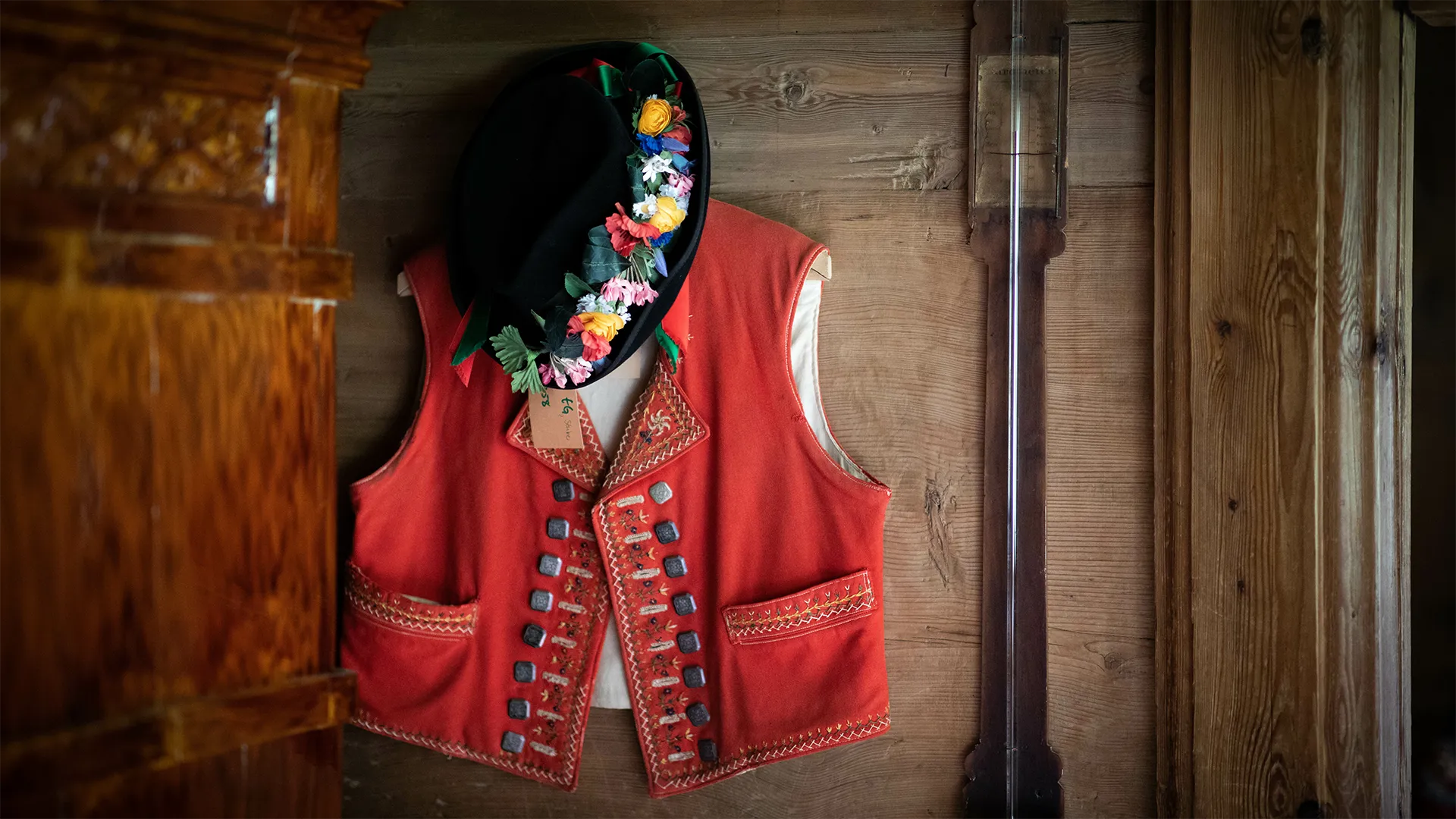 Ein volkstümliches Gilet aufgehängt an einem Nagel an der Holzwand.