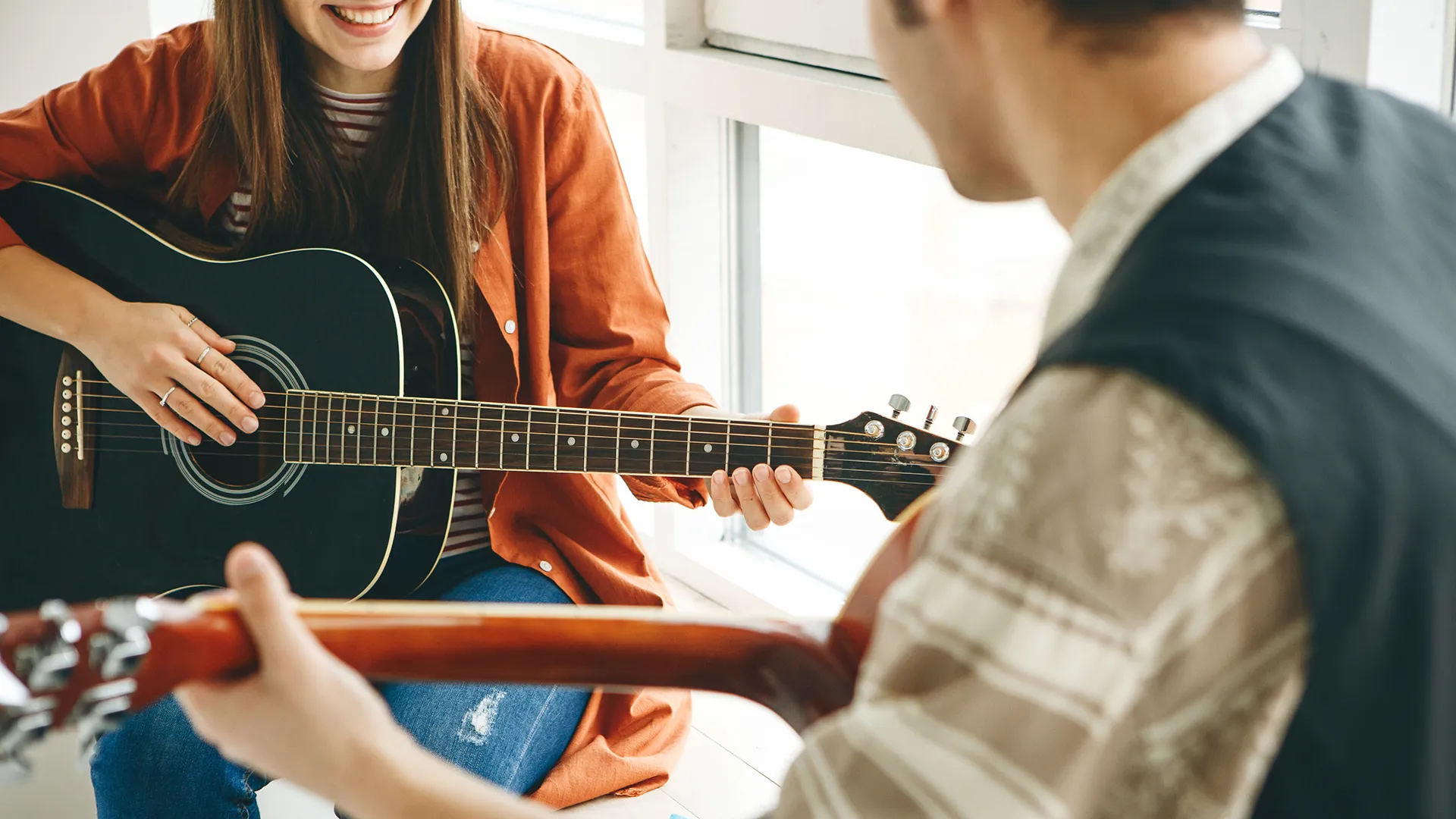 Zwei Personen spielen auf der Gitarre.