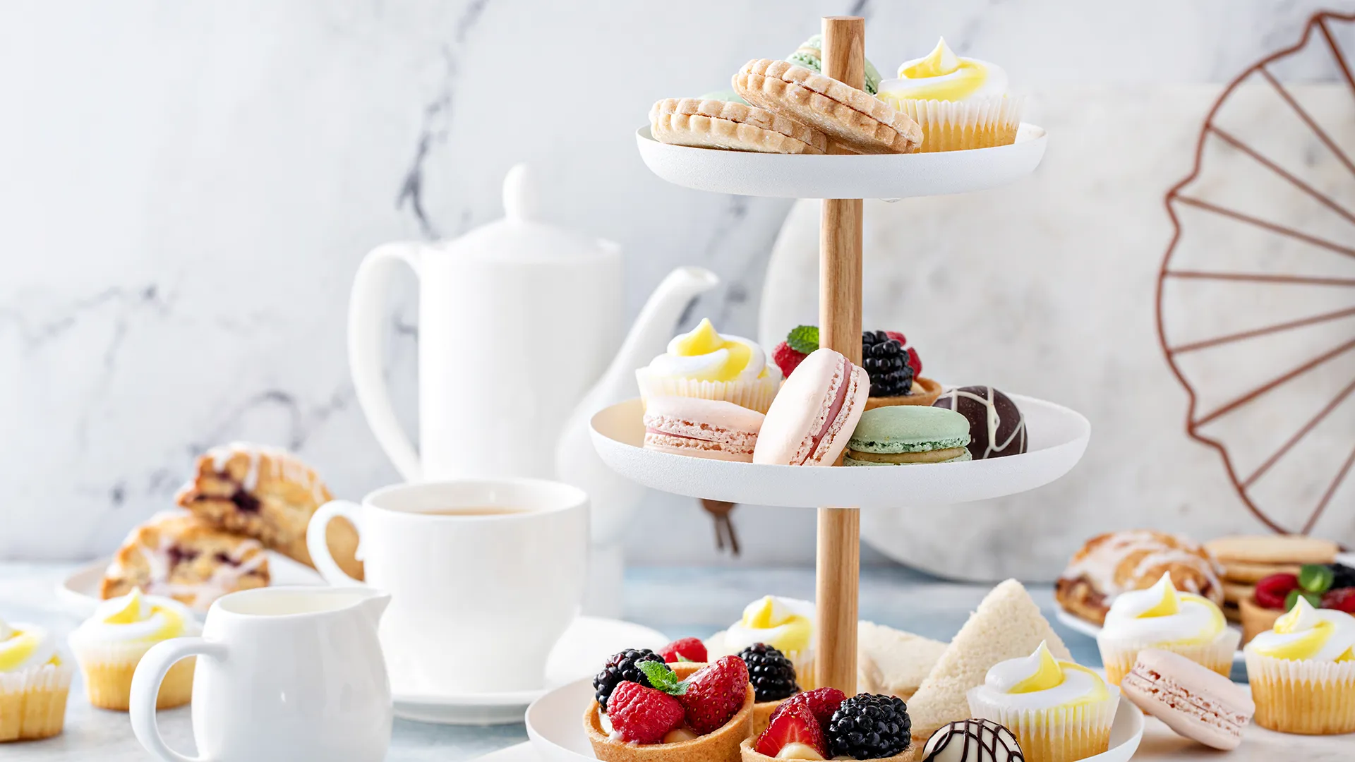 Etagere mit verschiedenen Dessert-Variationen, umgeben von Teegeschirr.