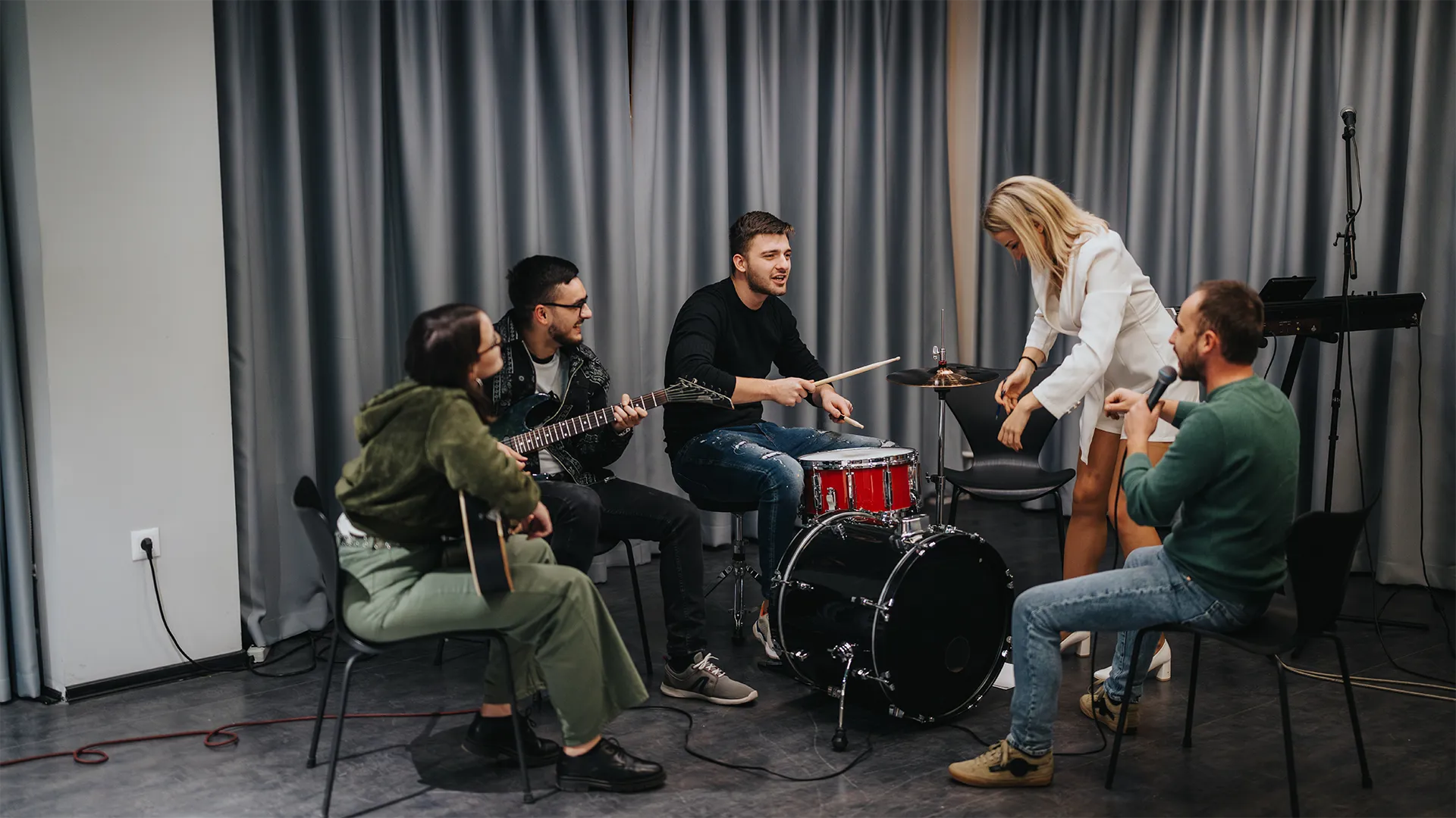 Fünf Personen spielen verschiedene Instrumente in einer Band.