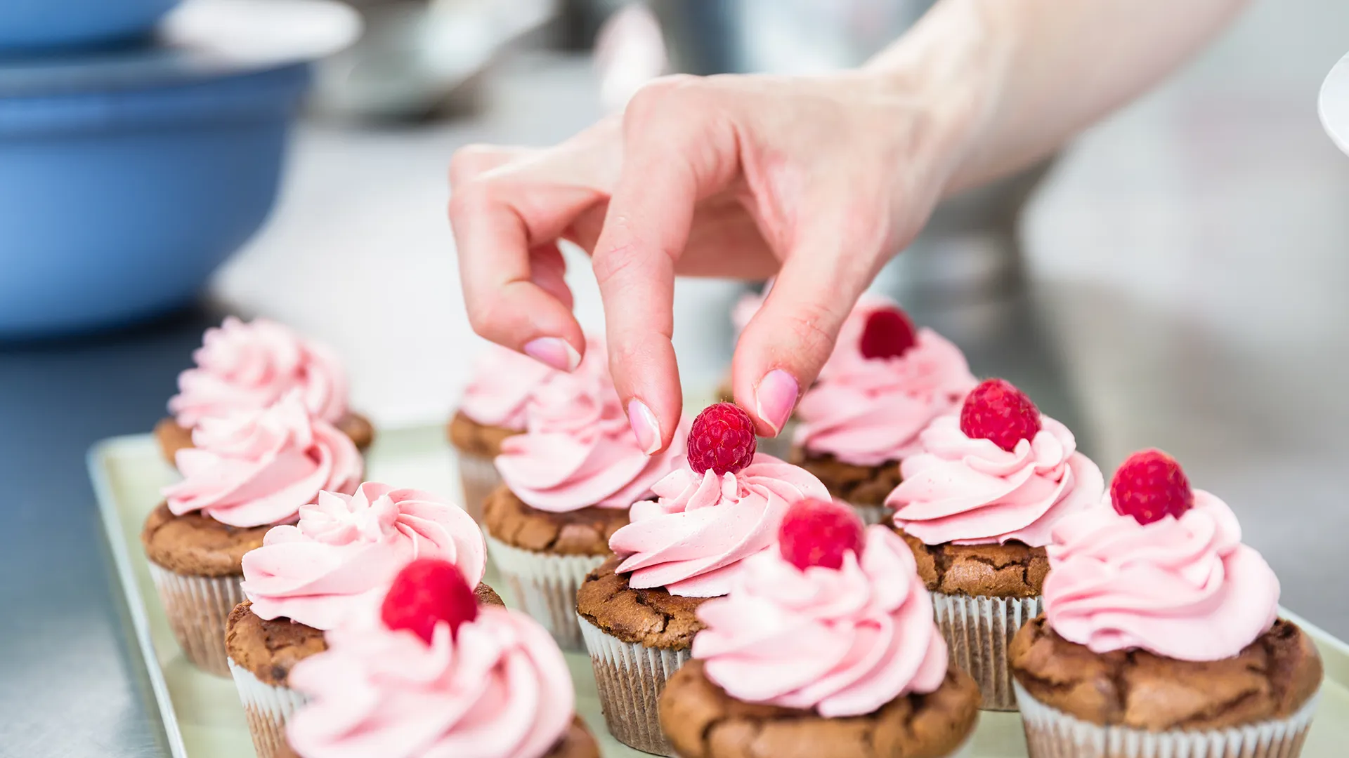 Eine Person dekoriert Patisserie-Desserts mit Himbeeren.