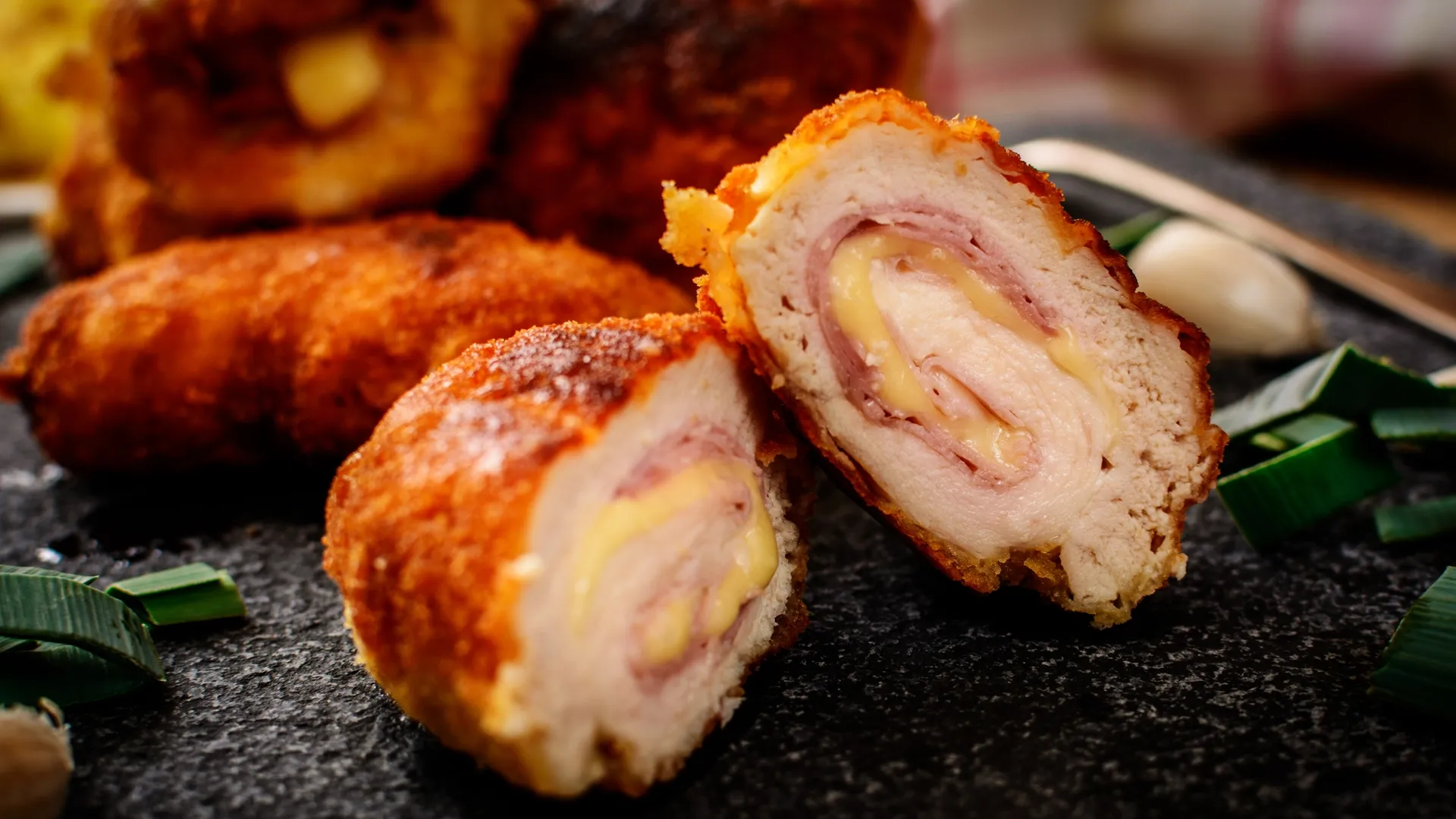 Cordon Bleu, gefüllt mit Schinken und geschmolzenem Käse, serviert auf einer Schieferplatte.