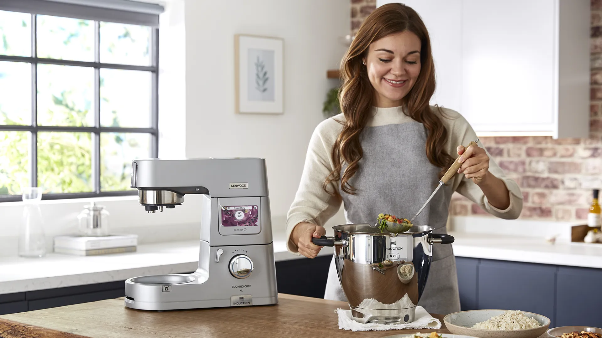 Eine Frau kocht ein Gericht mit einer Kenwood-Maschine.
