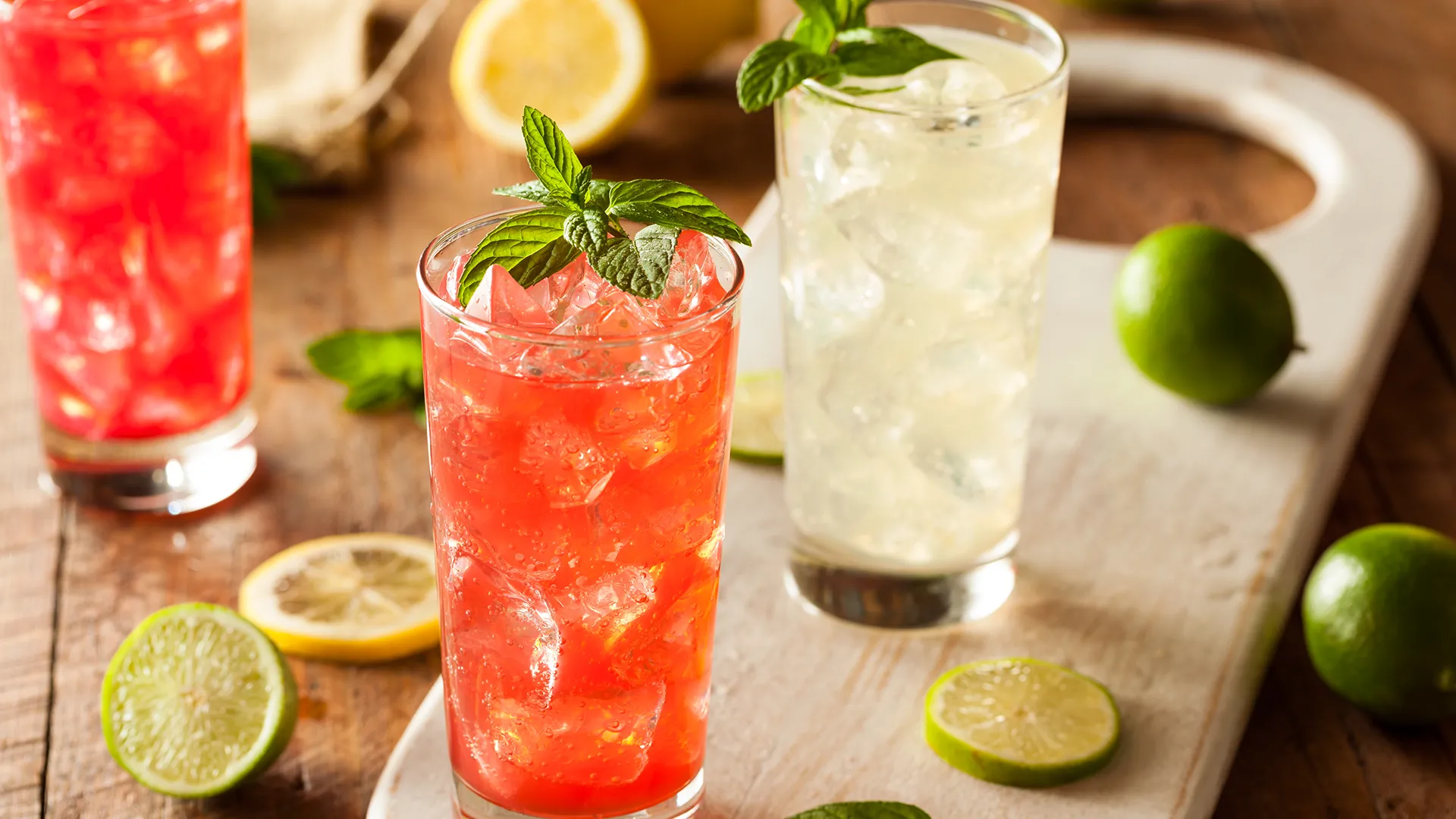 Zwei Mocktails arrangiert auf einem Holztablett mit Limettenschnitzen.