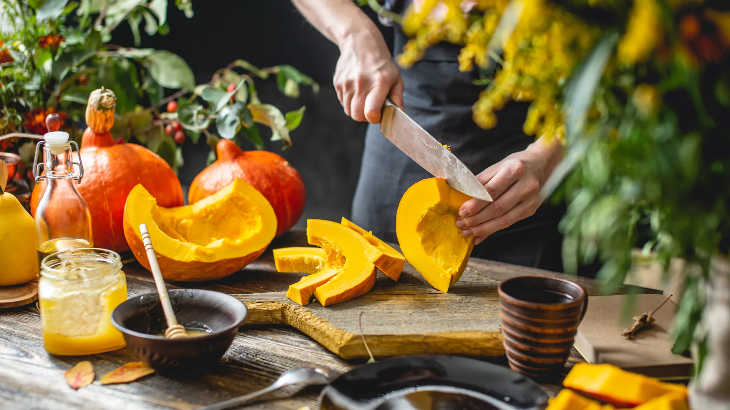 Eine Person schneidet einen Kürbis in mehrere Stücke.