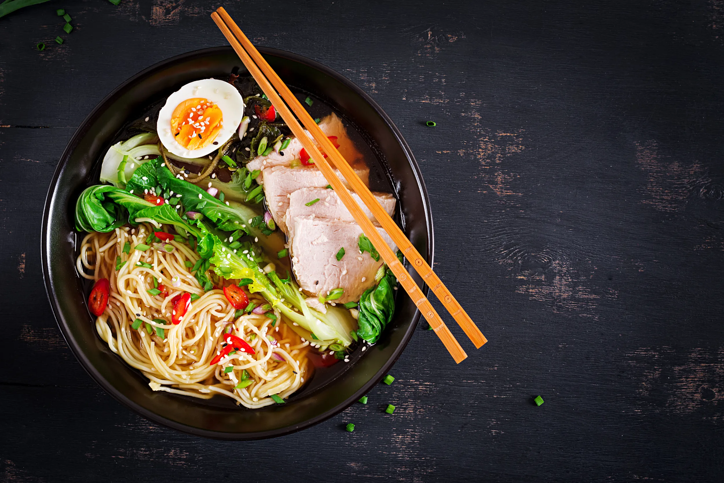 Eine Schale mit Ramen, Fleisch und Ei. Essstäbchen liegen auf der Schale.