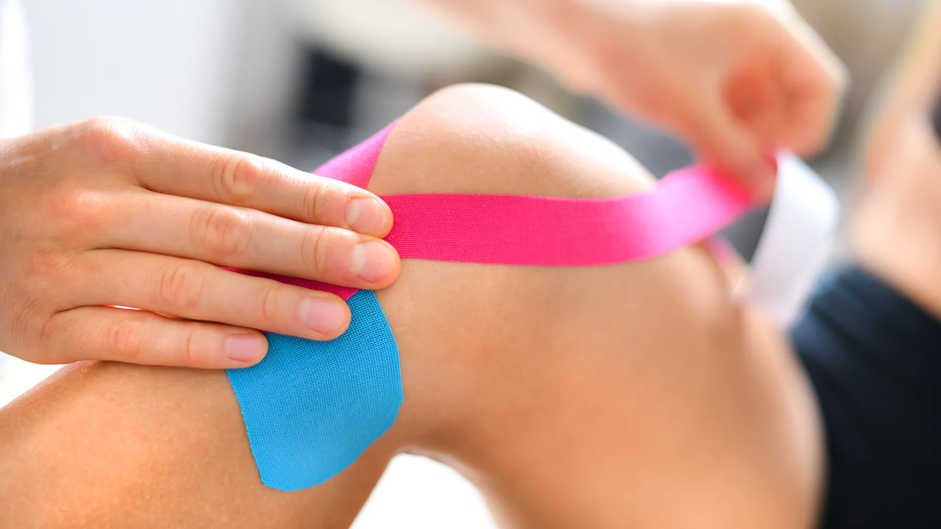 Knie mit verschiedenfarbigen Tapes zur Unterstützung.