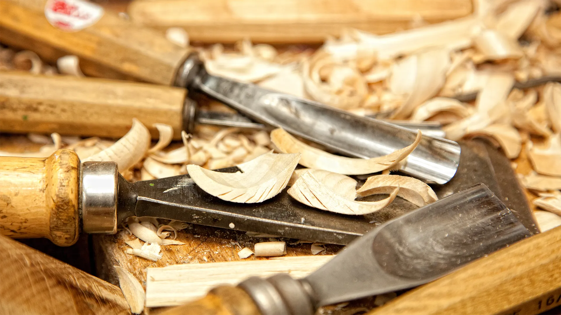 Schnitzutensilien mit Holzspäne liegen auf dem Tisch.