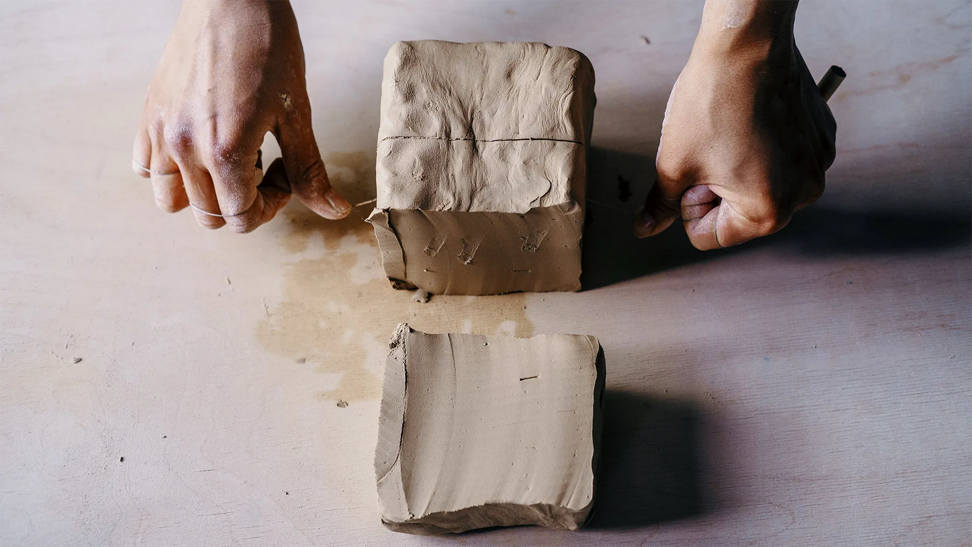 Eine Person schneidet einen Tonblock in Stücke.