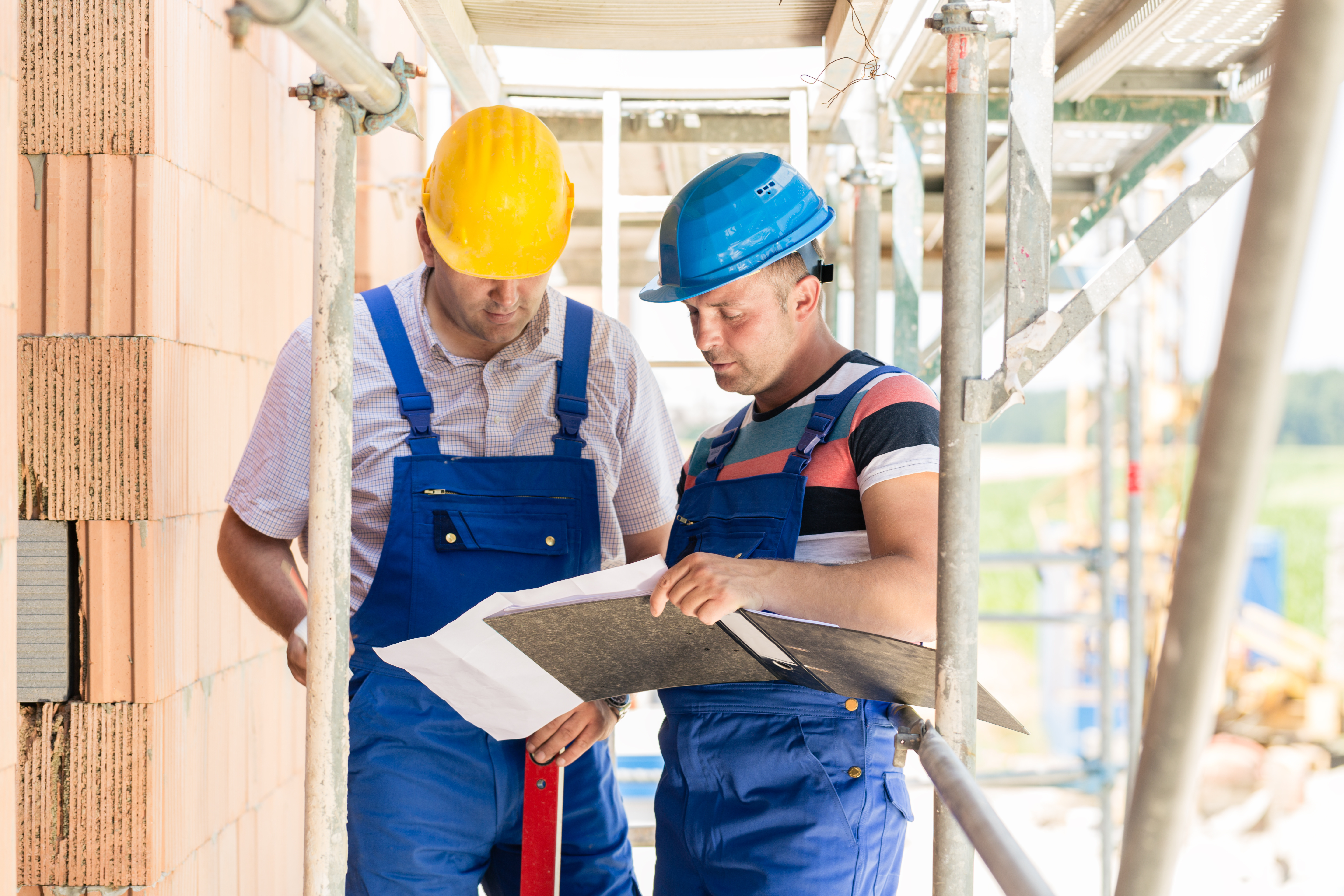 Zwei Mitarbeitende auf einer Baustelle besprechen gemeinsam Unterlagen