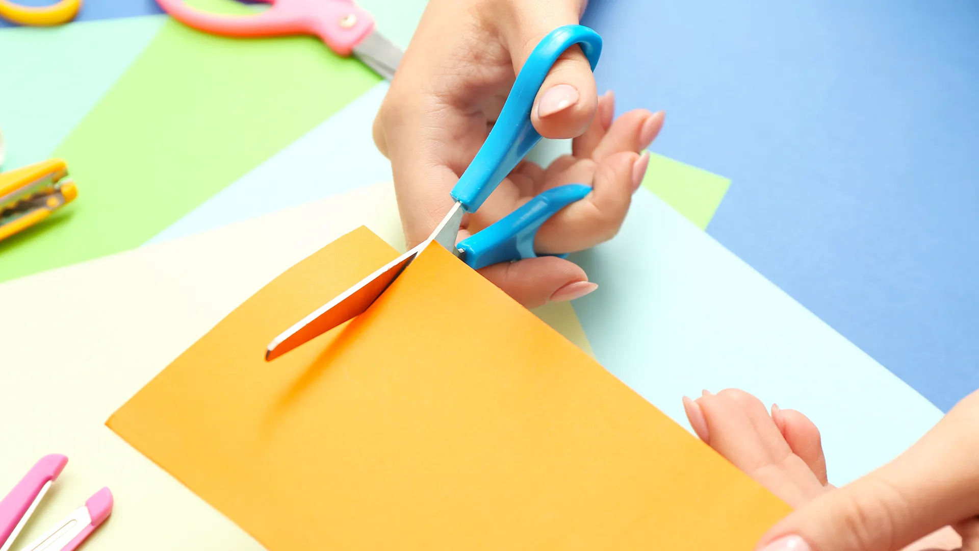 Eine Person macht einen Scherenschnitt mit farbigen Papier.