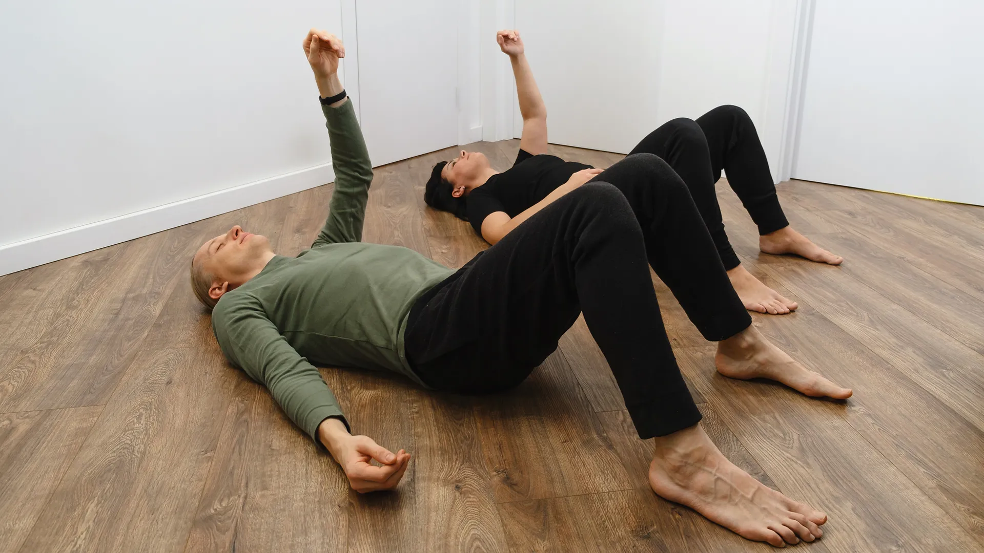 Personen führen Bewegungsübungen auf dem Boden durch, die Teil der Feldenkrais-Methode sind.