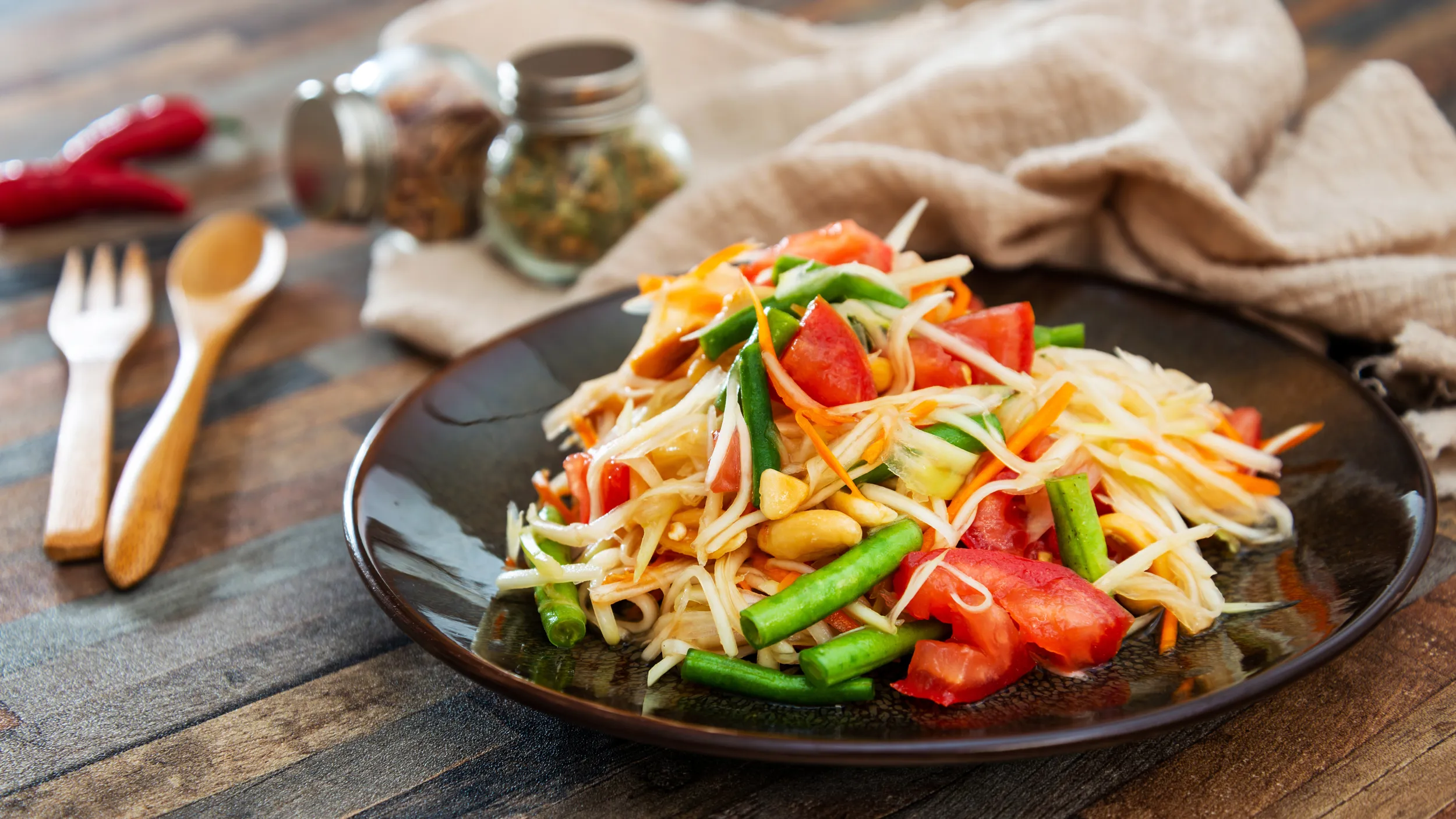 Ein thailändischer Papaya-Salat mit diversem Gemüse, serviert auf einem Teller.