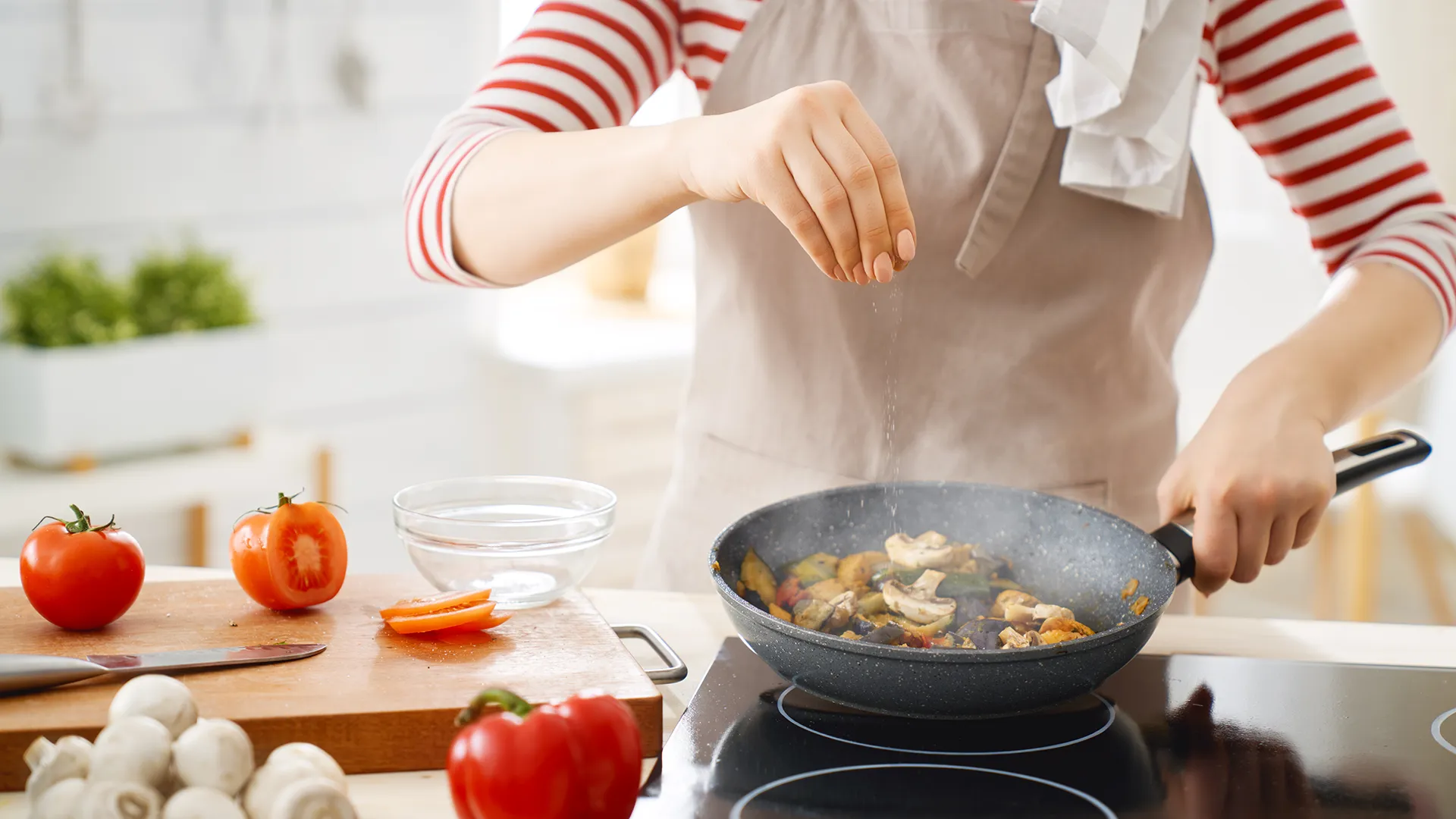 Eine Frau kocht ein Gericht in einer Bratpfanne.