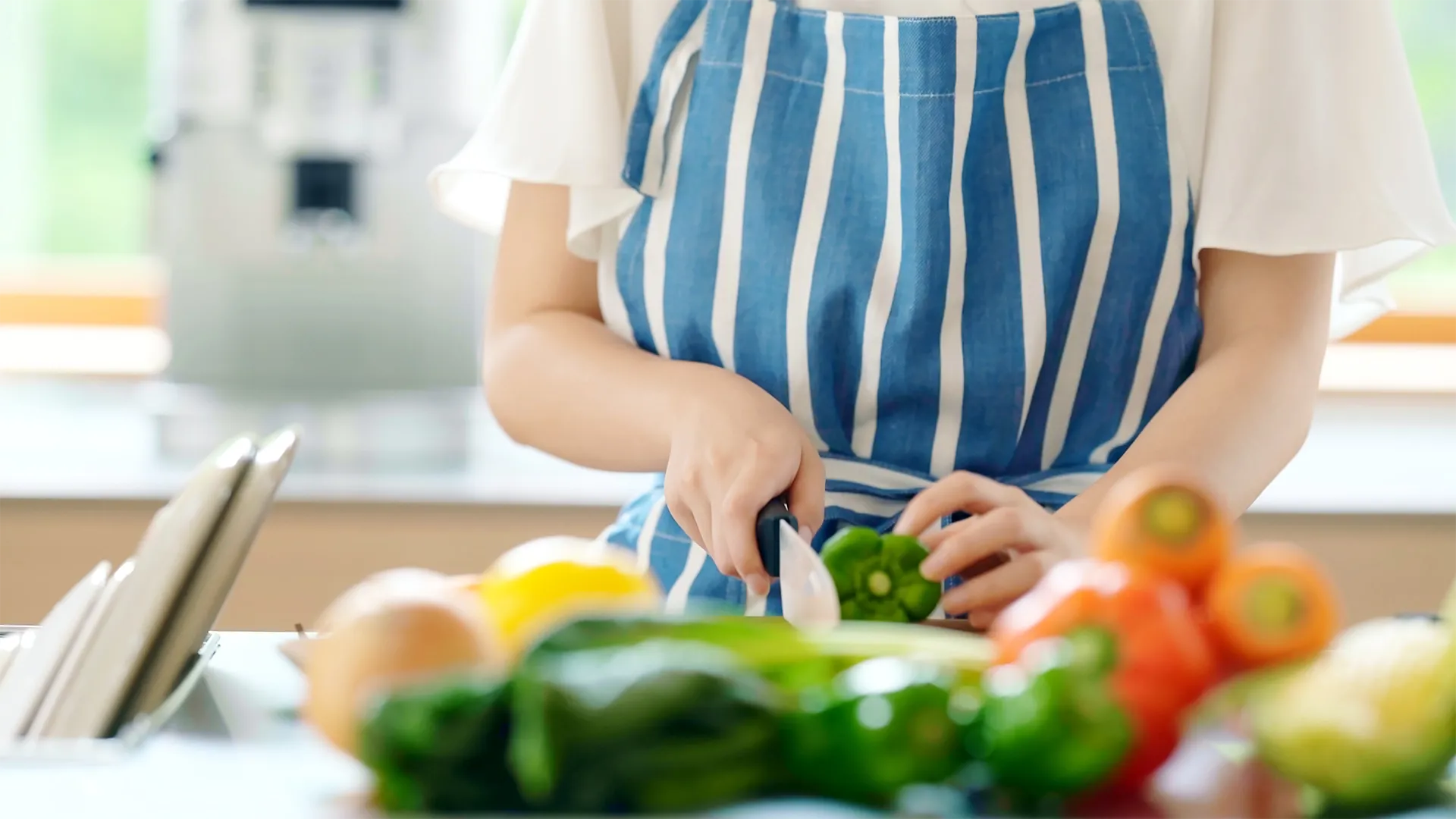 Eine Person schneidet eine Peperoni in Stücke.