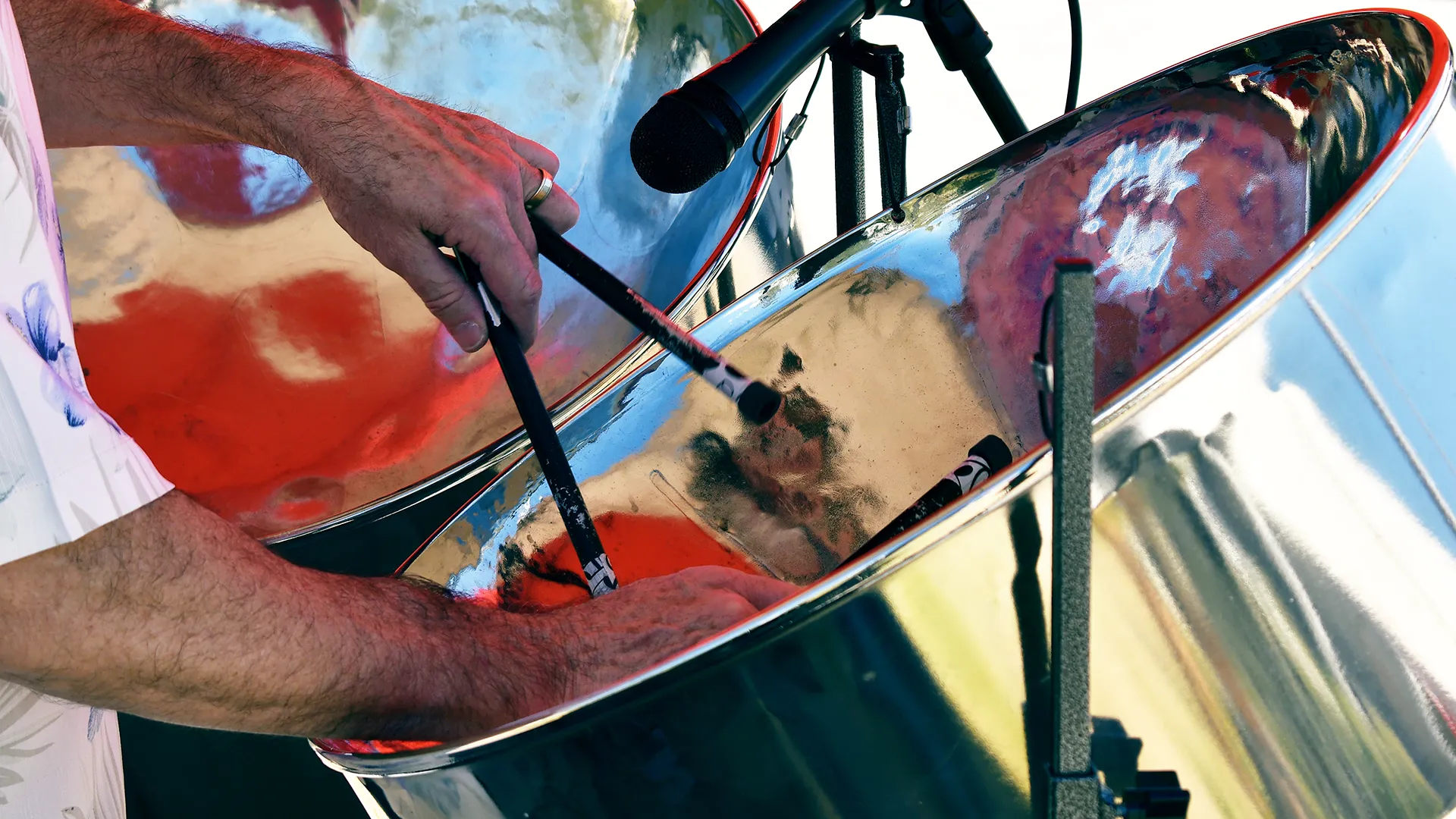 Ein Mann schlägt mit zwei Schlägeln auf das Steeldrum.