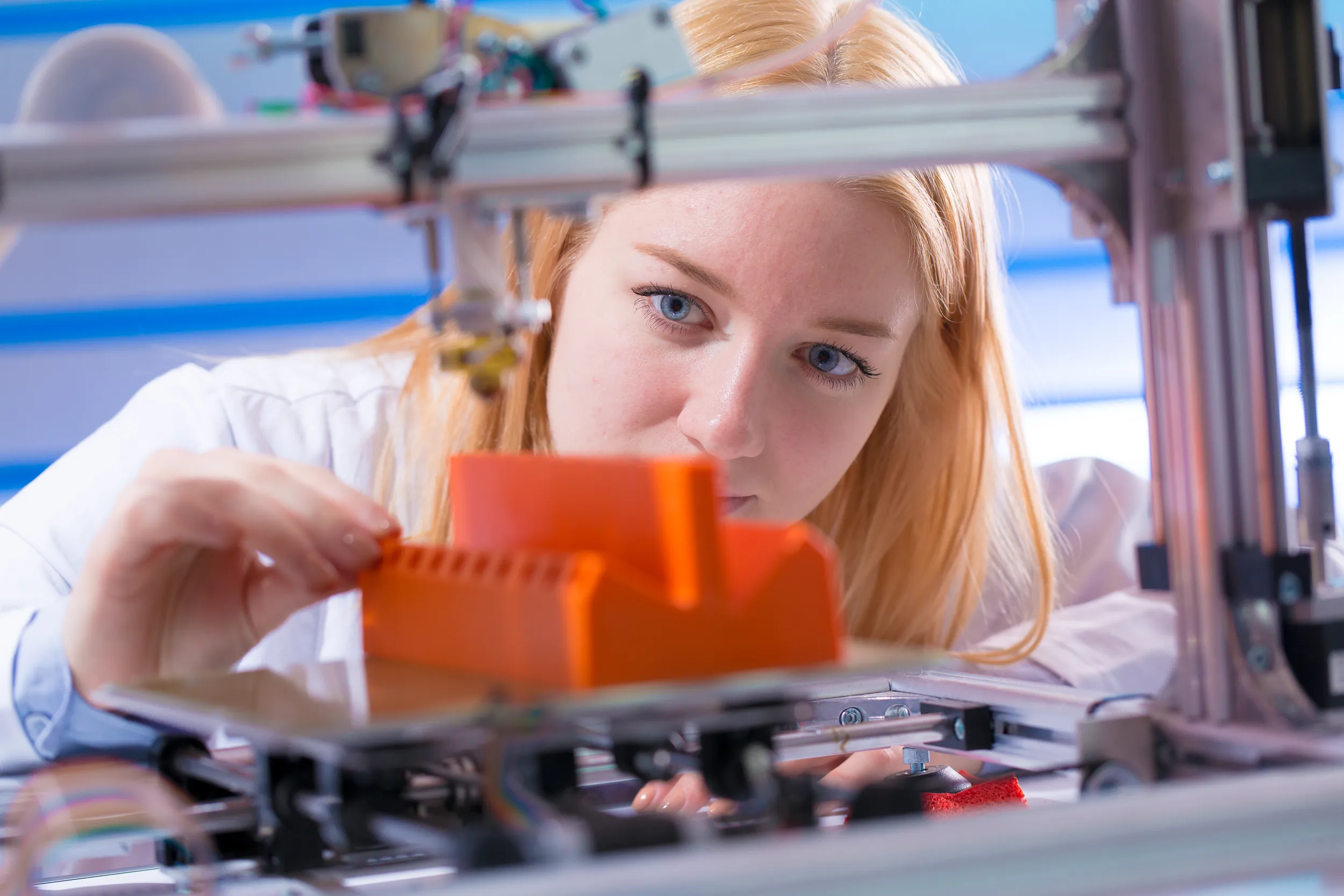 Frau schaut einem 3-D Drucker zu