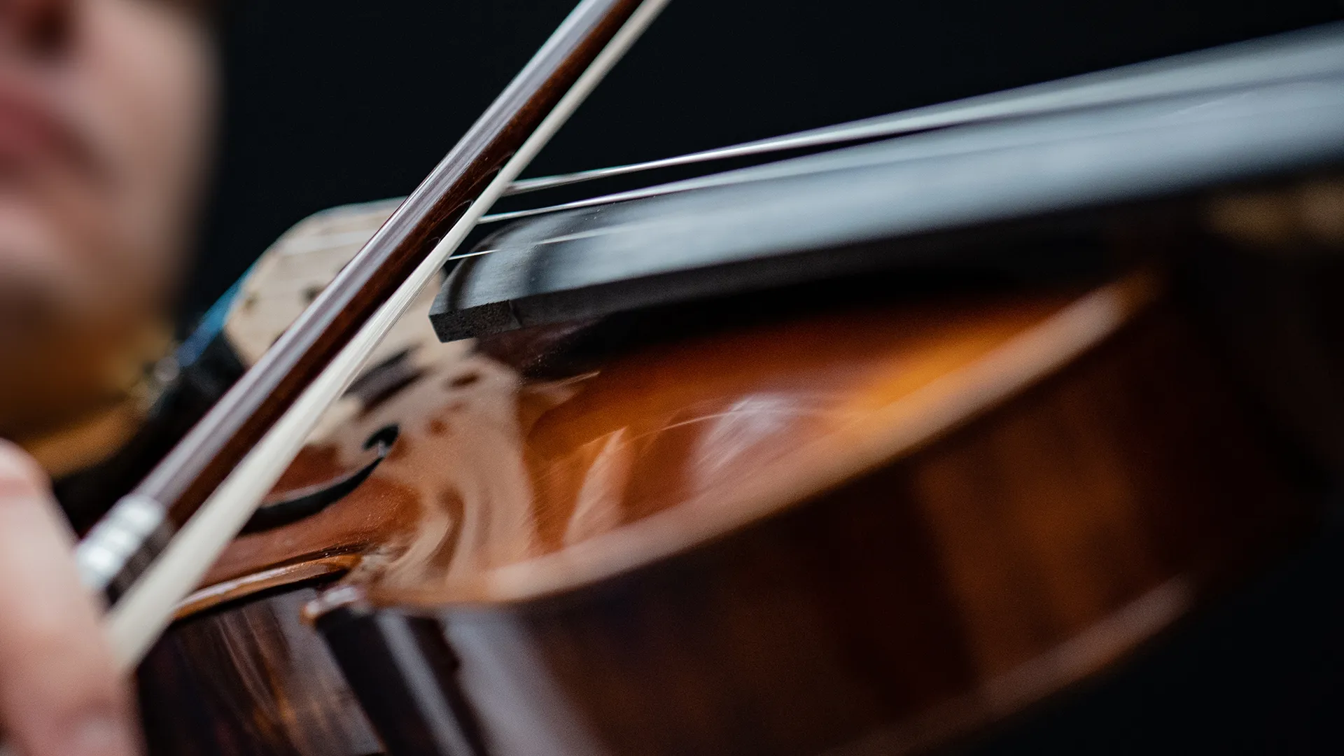 Eine Person streicht mit dem Bogen über die Saiten der Viola.